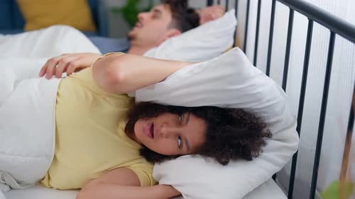 Une belle femme latino-américaine se sent frustrée par le fait que son mari ronfle pendant son sommeil.