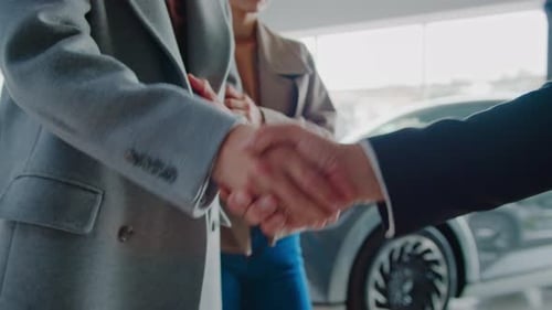 Young Man Shakes Manager Hand Visiting Car Dealership with Wife
