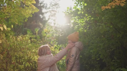 Mutter spielt mit den Haaren ihrer Tochter im sonnenbeschienenen Herbstwald