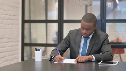African Businessman Writing a Letter in Office