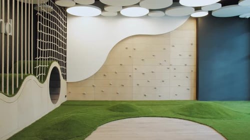 Dolly Shot d'une salle de jeux intérieure vide avec plafond arrondi, pelouse verte et mur d'escalade pour enfants