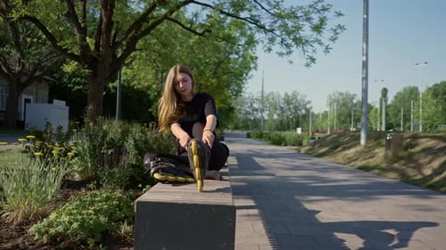 young beautiful girl in park tying laces on roller skates before skating workout active lifestyle
