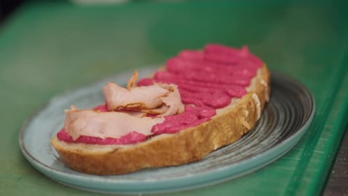 Chef Preparing Open Sandwich with Pink Spread and Meat