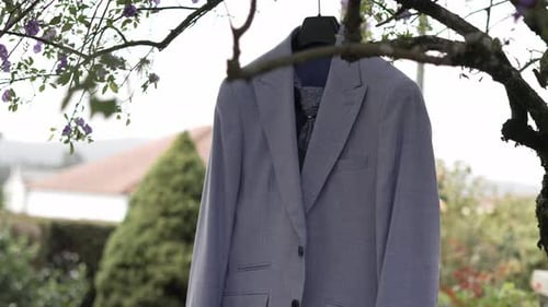 Blue suit hanging on a tree branch outdoors, surrounded by nature