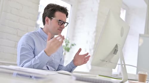 Frustrated Man Working at Computer in Bright Office