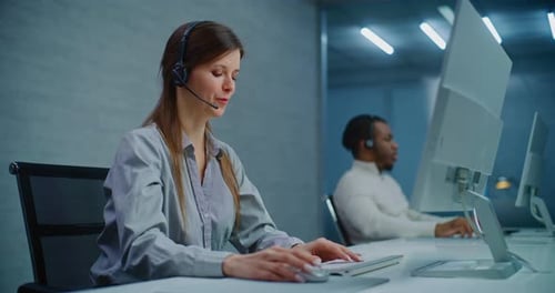 Call Center Female Hotline Operator Talks on Headset with Customer Works on Computer