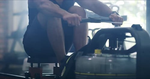 4k video footage of a handsome young man working out with a rowing machine in the gym