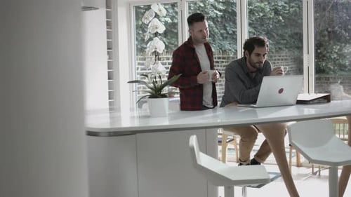 Two Men Using Laptop in Modern Kitchen