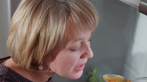 Woman Tastes Food with a Spoon Close Up