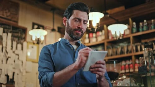 Caucasian Male Owner Writing Down Shopping List While Standing Near Bar Counter