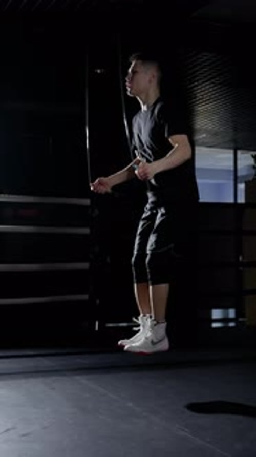 Fit Man Doing Jump Rope Exercise in Dark Gym