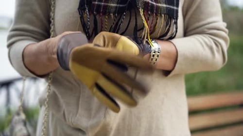 Closeup Senior Female Hands Putting on Stylish Leather Gloves Outdoors Front View Unrecognizable