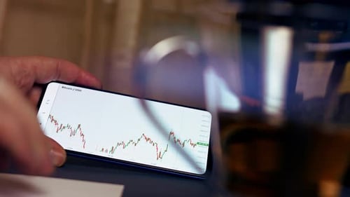 Analyzing Crypto Data On Phone at Office Desk