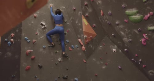 Athlete Female Rock Climber Exercising on Indoor Climbing wall