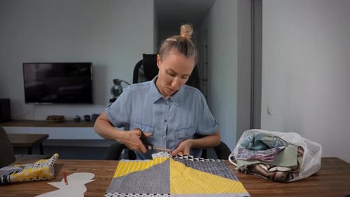 Woman Cutting Fabric Pieces Using Templates and Scissors Preparing for Sewing