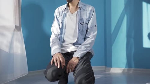 Young Man Sitting Down in Brightly Lit Room