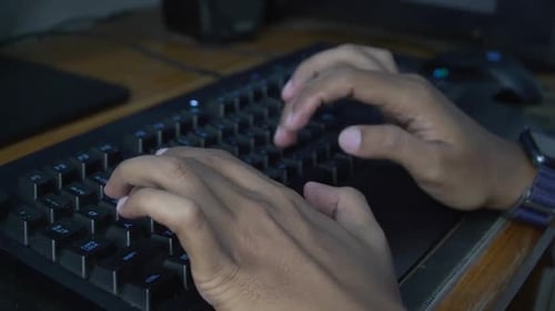 Hands Typing on Keyboard with Blue Illumination