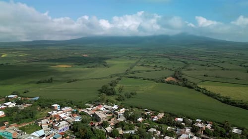 Panorama-Luftaufnahme von Getreidefeldern. Grüne Landschaft mit Hügeln und bewölktem Himmel im Hintergrund.