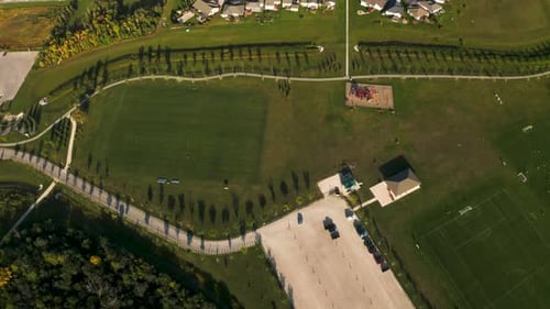 Top down dolly right 4k shot of a beautiful lush green soccer park with walking paths and play struc