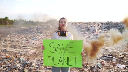 Young Adult Holding 'Save the Planet' Sign in Dump