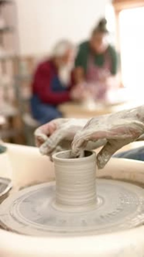 Mains d'un potier afro-américain utilisant un tour de potier dans un studio de poterie, Ralenti