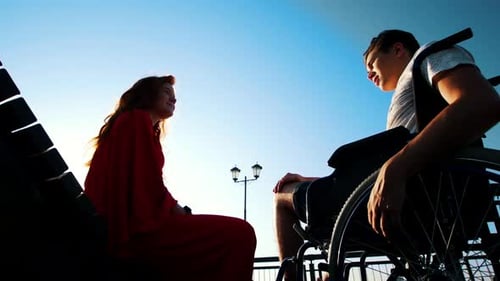 Woman and Man in Wheelchair Talking on a Bench