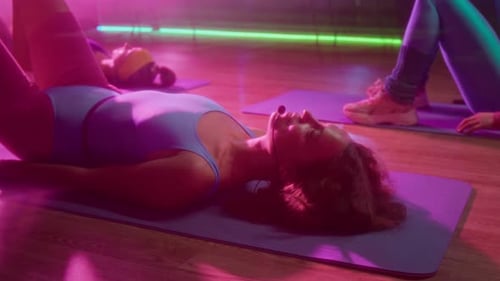 Female Fitness Instructor Performing Glute Bridge during 1980s Group Workout