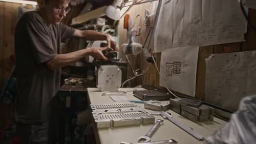 Technician Attaching Component to Cutting Lathe in Garage