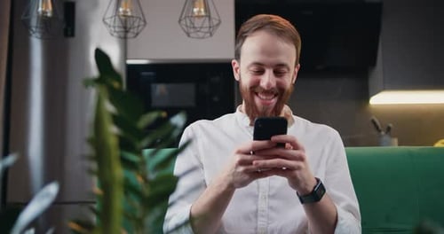 Man Relaxing on Couch Using Smartphone