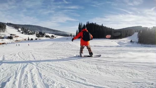 Snowboard Winteraktivität Snowboarder fährt auf der Piste in den Bergen in Zeitlupe bergab