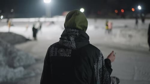 Back View of Skater Carrying Boots Walking Across Winter Rink at Night