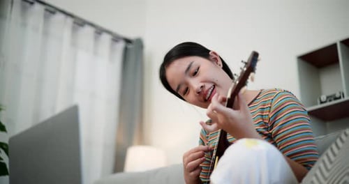 Woman plays ukulele and sings at home