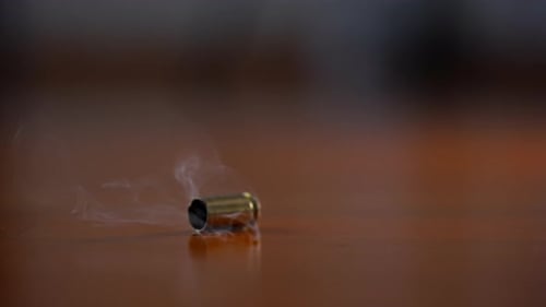 Geschossgehäuse, das in Zeitlupe auf eine Holzoberfläche fällt, gebranntes Messinggehäuse prallt nach dem Schuss ab