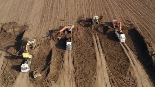 Excavators loading soil onto Trucks, Aerial view.