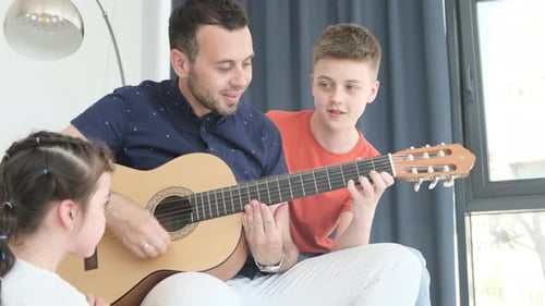 Man Plays Guitar With Children at Home