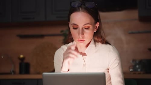 Young Woman Working at Laptop in Dim Home