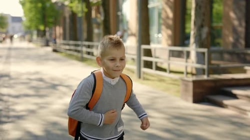 Männlicher Schüler rennt nach der Schule nach Hause, trägt Rucksack und trägt Freizeitkleidung
