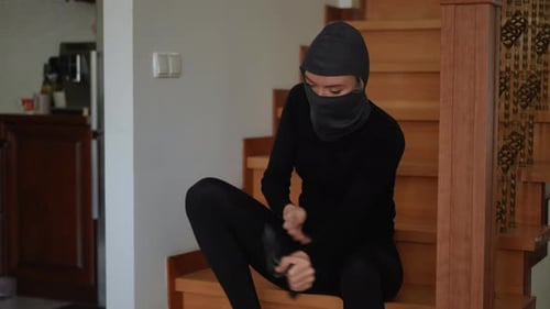 Woman Takes Off Balaclava and Sits on Stairs