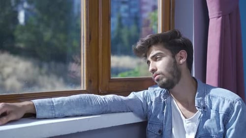Depressed man. The man is watching out the window.