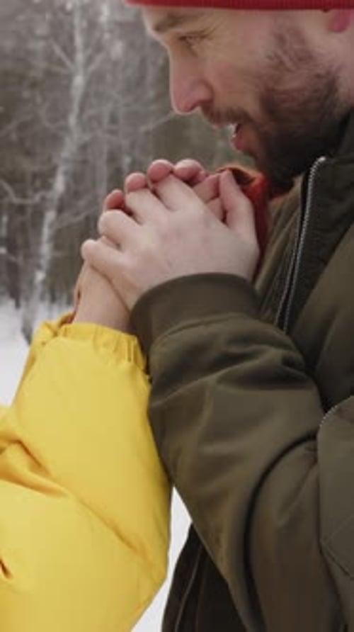 Couple Warming Hands in Snowy Winter Woods
