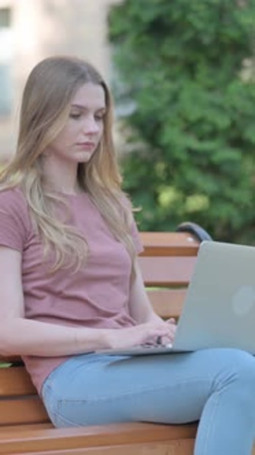 Woman Working on Laptop Outdoors on Park Bench