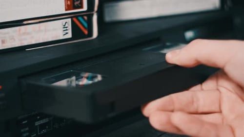 Male Hand inserta un casete VHS en un reproductor de vídeo VCR