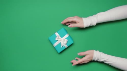 Man and Woman Exchange Christmas Gift in Blue Box on Green Background Top View