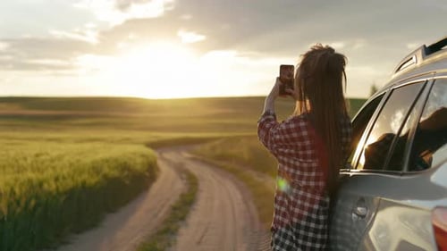 Woman with Car Taking Pictures in Rural Field