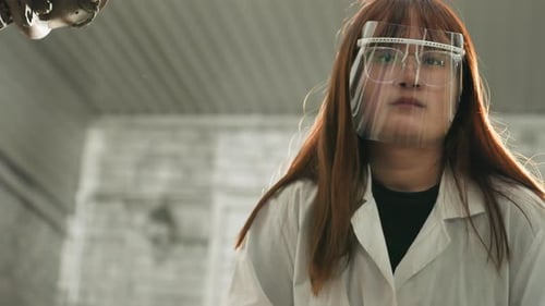 Lab Technician Observing Lifted Car and Taking Notes in Mechanical Workshop