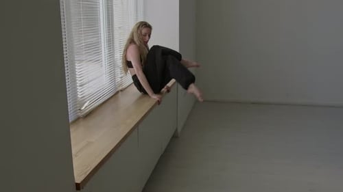 Anmutige Darstellerin übt Tanzbewegungen auf der Fensterbank im Studio