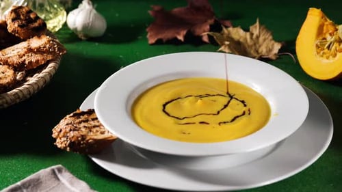 Cremige Kürbissuppe auf einem Teller verzieren
