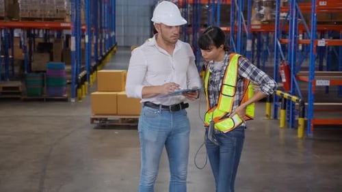Young woman talking with manager while signature document on clipboard in the warehouse at factory.