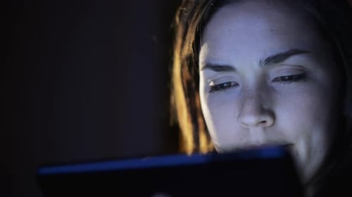 4k video footage of a young woman using a digital tablet late at night