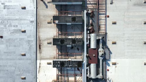 Industrial building rooftop with HVAC ventilation and air conditioning units along with pipes. Aeria